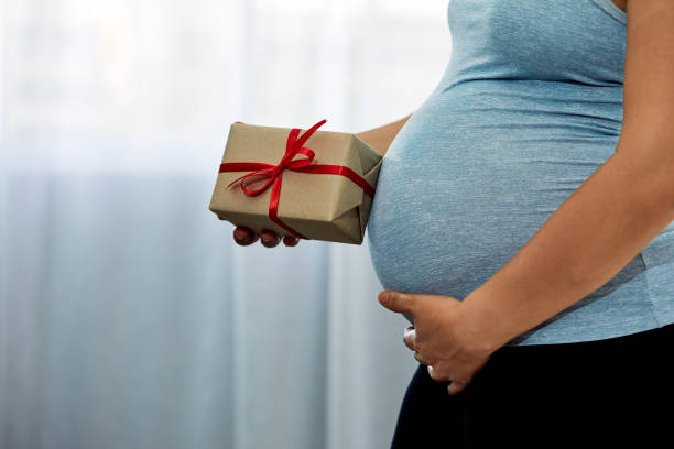 Pregnant Woman holding brown Gift Box in Her Cozy Bedroom with copy space Pregnant Woman holding brown Gift Box in Her Cozy Bedroom with copy space - Anticipating Joyful Motherhood cute pregnant woman with gift stock pictures, royalty-free photos & images