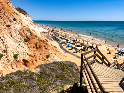 Nice stone beach and turquiose water of cote dAzur at summer morning with open traditional umbrellas, french riviera coast