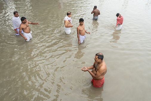 Hindu devotees perform the 'Tarpan' rituals standing on water during Mahalaya prayers, also known as Pitru Paksha, in the banks of Brahmaputra river on October 14, 2023 in Guwahati, Assam, India.  Mahalaya is a day to honor their ancestors and seek their blessings.