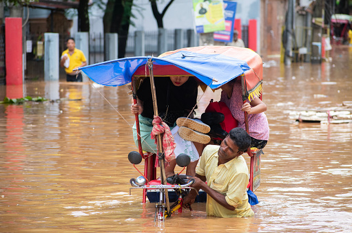 Commuters on a rickshaw to cross a waterlogged road after heavy rainfall, on October 6, 2023 in Guwahati, Assam, India. Severe water logging witnessed in Guwahati city following heavy rains, as the India Meteorological Department (IMD) predicted.