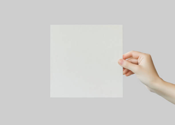 istock female hand holds empty square cardboard banner on grey background. 1742933344