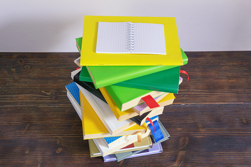 Stack of different multicolored colorful books on rustic table. Copy space