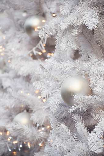 White decorations on artificial white Christmas tree with copy space