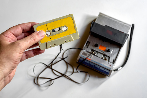 Hand holding a cassette tape that has become tangled in the player.