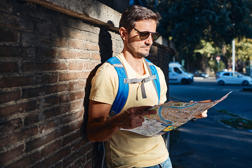 Young male tourist reading a map while exploring big city.