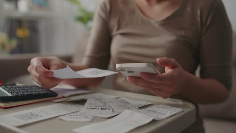 woman calculating receipts for her budget and spending on her phone, Closeup of female hands adding up monthly expenses