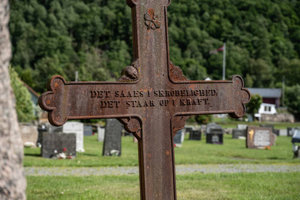 Lyngdal, Norway - July 06 2023: Old metal cross on a cemetery with inscription.
