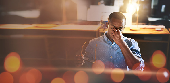 Black man, vision and night at office with burnout, bokeh and banner with glasses, IT consultant and deadline. Overtime, overworked and mockup space, developer with headache and work late with stress