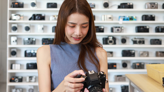 Close-up of a young woman holding a camera,A young woman examining a camera in a shop