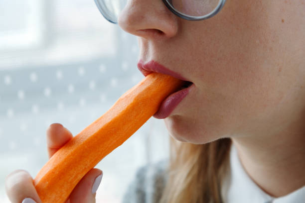 istock Young woman bites raw carrot, 1743084868