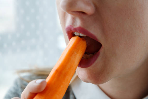 istock Young woman bites raw carrot, 1743084873