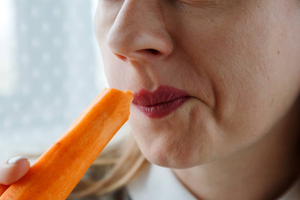 istock Young woman bites raw carrot, 1743084882