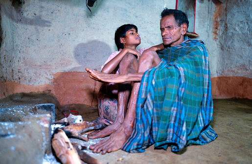Father and daughter from the Bonda tribe of the Indian region of Odisha in front of the fireplace. Father and daughter from the Bonda tribe of the Indian region of Odisha in front of the fireplace. The girl leans on her father's knee and looks at him with