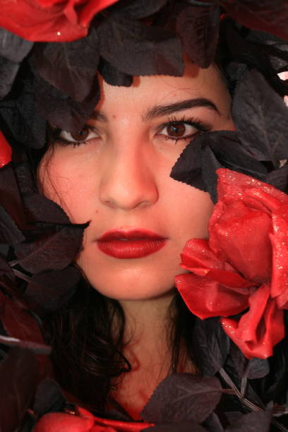 A close up of a Mexican model ready for Day of the Dead celebrations. She has black wavy hair and red roses.