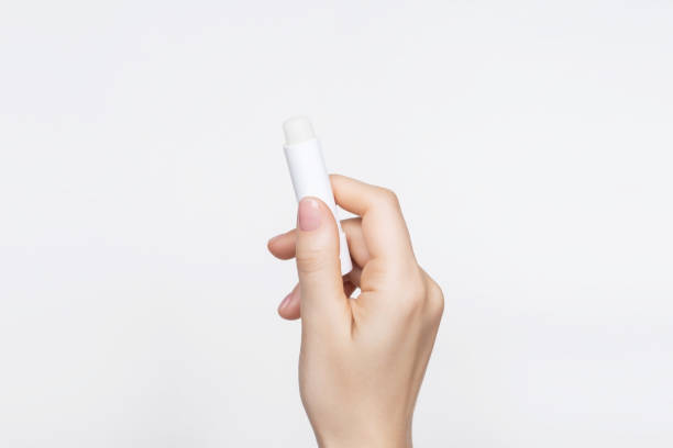istock Female hand holds hygienic moisturizing lipstick on gray background. lip care concept, copy space 1743122607