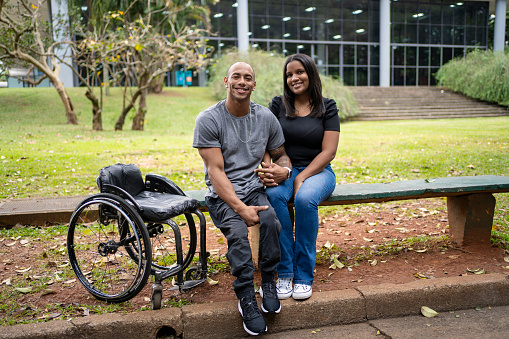 Disabled man in wheelchair and his wife in a public park