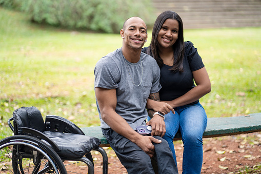 Portrait of man in wheelchair and his wife in a public park