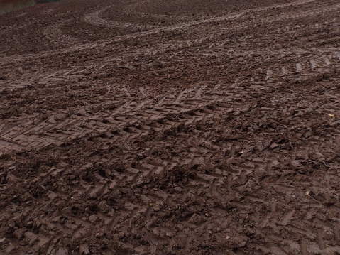 Imprints of the tractor's passage in a field. Tractor's marks on a wet ground. Traces left by the tractor in the damp soil