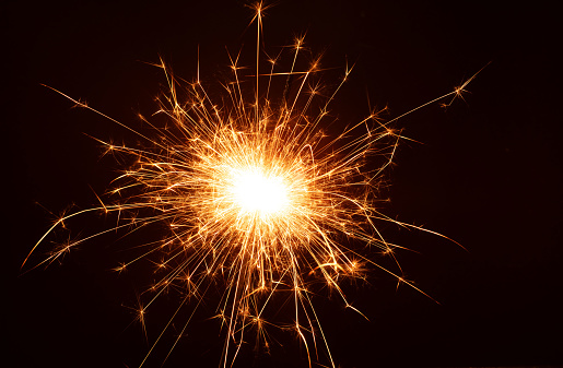 photo amidst the black background, a glowing sparkler ignites the atmosphere, creating a celebration sparks leaves a trail offering a striking image with copy space. burning, glowing, close-up, abstract