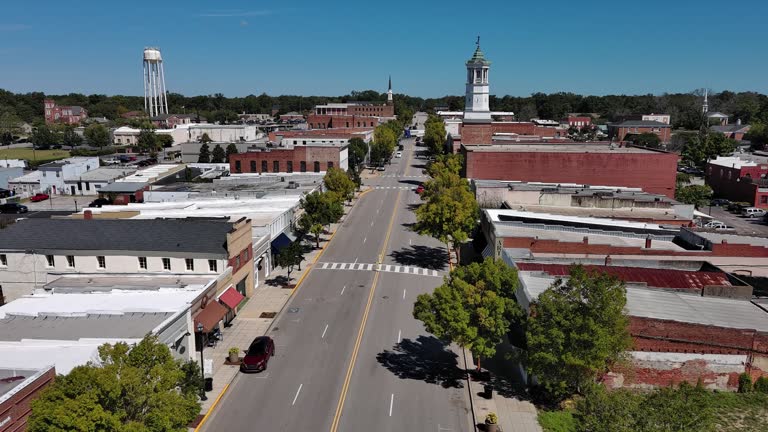 Suburban neighborhood with shops and cafes alongside the Broad Street in Camden, South Carolina. Water tower stand overtop blue sky horizon. Aerial footage with forward-descending-ascending camera motion