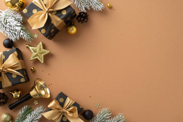 Spark your creativity with this Christmas scene. Top-view image of elegant gift packages, black and gold balls, star, sparkling confetti, delightful bell, frosted fir twigs on terracotta, text space