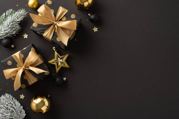 istock Sumptuous Noel blessings inspiration. Top view of lavish presents, extravagant tree embellishments, balls, sparkling confetti, frosted evergreen branches on black backdrop with room for greetings 1743172297