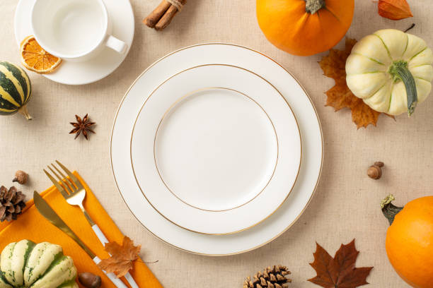 istock Fall-inspired dining concept: Overhead shot features plates, cup, and cutlery set amidst pumpkins, anise, acorns, and physalis. The pastel beige background invites your text or promotional content 1743172342