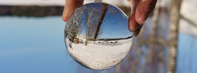 Photography of the beautiful clear crystal ball. Russian nature in focus. Miracle warm view. Human hand holding crystal ball. Photography is full of spring sunlight. Tourist resort. Close up.