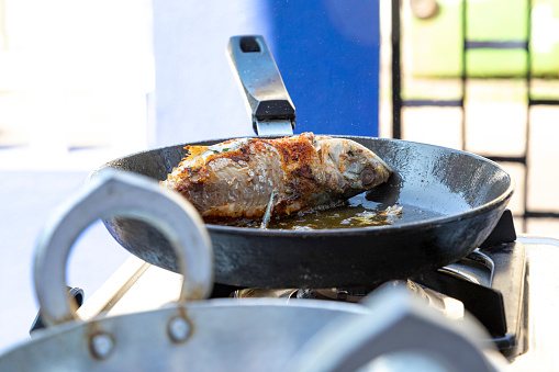 These images capture the dynamic process of Indian cooking, focusing specifically on fish as the main ingredient. A lively flame flickers underneath the pan, lending an intense heat that's fundamental to many Indian cooking techniques. The fish is seen sizzling away, its flavours enhanced by an array of vibrant spices sprinkled around it. The photograph aims to offer viewers an immersive experience into the world of Indian cuisine, highlighting the complex layering of spices and the skilful use of fire to create dishes that are as visually compelling as they are flavourful.