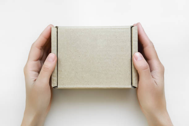istock female hands holding a small cardboard box on a white background. packaging and delivery concept, top view 1743214741