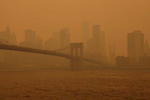 Brooklyn bridge and manhattan bridge in New York City are covered by haze, smoke and fire smoke. They look amber.