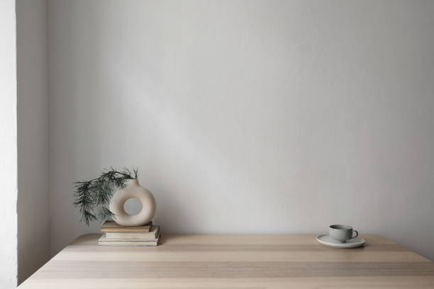 istock Modern vase on old books with pine tree branches.Cup of coffee on beige table.Empty white wall background in soft light. Minimal Christmas home decor. Modern scandinavian interior. Winter design. 1743263253