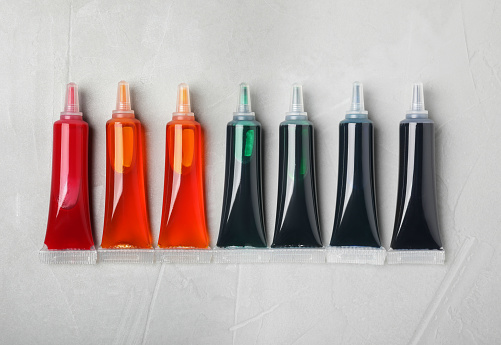 Tubes with different food coloring on white background, flat lay