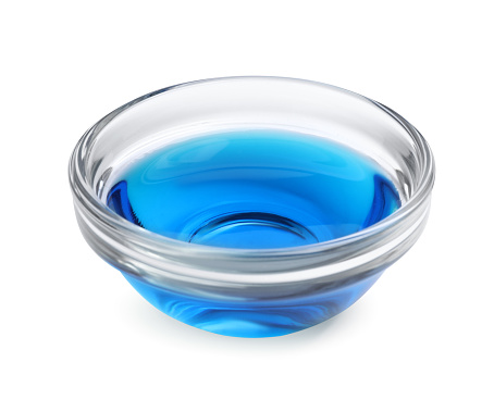 Glass bowl with light blue food coloring isolated on white