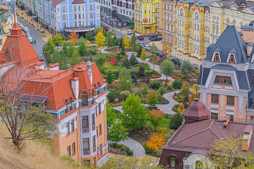 Park in the fall amidst old European architecture. Multicolored trees in the park top view of multicolored houses. Kyiv, Ukraine, 10-18-2023
