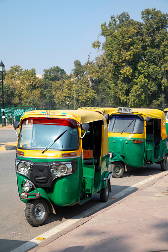 This image showcases a Tuk Tuk in Delhi, one of the quintessential modes of transport in India's bustling capital. Known for their agility and ability to manoeuvre through the city's crowded streets, Tuk Tuks are an integral part of Delhi's urban landscape. Painted in vibrant colours and often decorated with trinkets or stickers, these three-wheeled vehicles add a dash of character to the city's transportation scene. The photograph aims to capture the essence of daily life in Delhi, focusing on the Tuk Tuk's unique design and the role it plays in the commotion and vibrancy of the city.