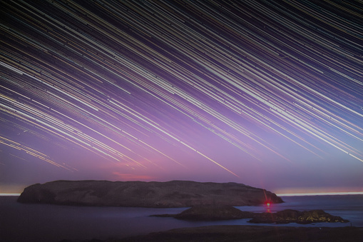 Startrails in pink night sky over the Calf of Mann and Sound on the Isle of Man