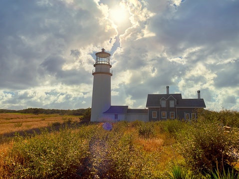 Dramatic sky and sun behind the Highland Lighthouse at Cape Cod national seashore.