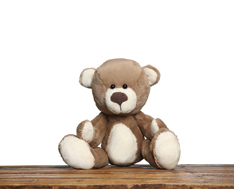 Cute teddy bear on wooden table against white background