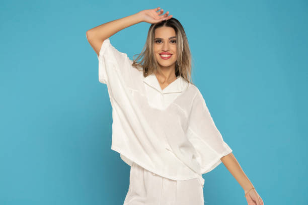 istock young modern smiling woman in white pants and blouse posing on blue background. front view 1743355265