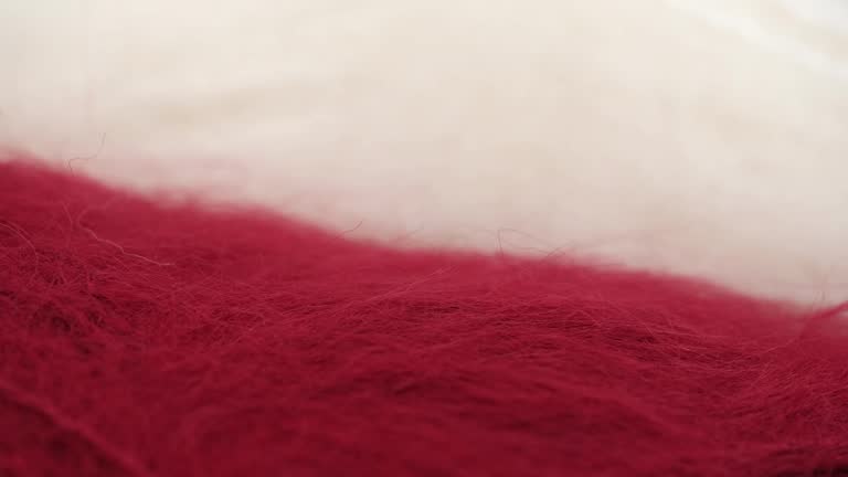 closeup of fluffy natural wool in red and white for knitting and crocheting, rotation. macro.