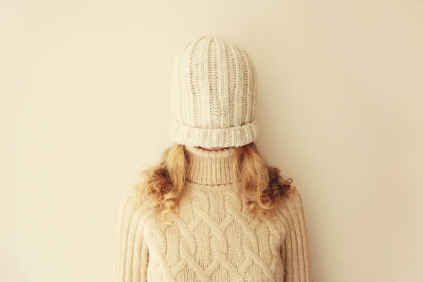 istock Cheerful funny woman having fun, pulling winter hat over her face covering her eyes in warm soft knitted clothes, sweater on beige studio background 1743380300