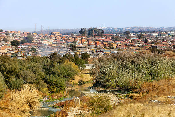 The Jukskei river going through the township of Alexandra (Alex) was established in 1912 and is close to the center of Johannesburg. It covers an area of over 800 ha (including east bank) and its infrastructure was designed for a population of about 70,000. Current population estimates vary widely and have been put at figures ranging from 180,000 to 750,000. Its original stands of size of 500-600 sq.m are characterized by sizeable houses of reasonable stock but usually with 3 – 6 additional separate rooms built in the original gardens, each usually housing an additional family who rent from the main householder. The additional rental units, which provide a significant income to the main householder, are termed “backyard shacks” although many are of brick or block construction of reasonable quality. There are an estimated 20,000 shacks of which approximately 7,000 are located in “backyards”