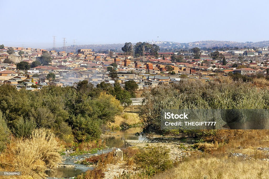 Alexandra township and Jukskei river The Jukskei river going through the township of Alexandra (Alex) was established in 1912 and is close to the center of Johannesburg. It covers an area of over 800 ha (including east bank) and its infrastructure was designed for a population of about 70,000. Current population estimates vary widely and have been put at figures ranging from 180,000 to 750,000. Its original stands of size of 500-600 sq.m are characterized by sizeable houses of reasonable stock but usually with 3 – 6 additional separate rooms built in the original gardens, each usually housing an additional family who rent from the main householder. The additional rental units, which provide a significant income to the main householder, are termed “backyard shacks” although many are of brick or block construction of reasonable quality. There are an estimated 20,000 shacks of which approximately 7,000 are located in “backyards” Johannesburg Stock Photo