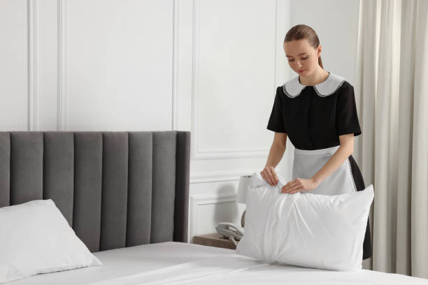 istock Young maid making bed in hotel room. Space for text 1743429818