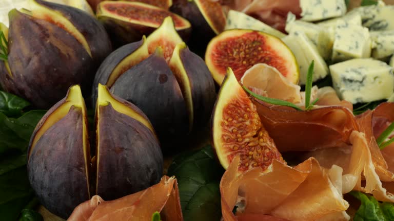 Figs, jamon, spinach leaves and blue cheeses on a wooden board. Snacks set.
