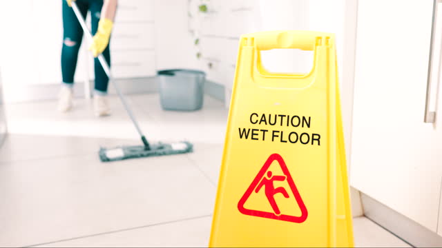 Wet, floor and sign for caution, cleaning and attention for safety in room with maid, housekeeping and risk of falling on ground. Cleaner, warning and janitor with mop, water and bucket for hygiene