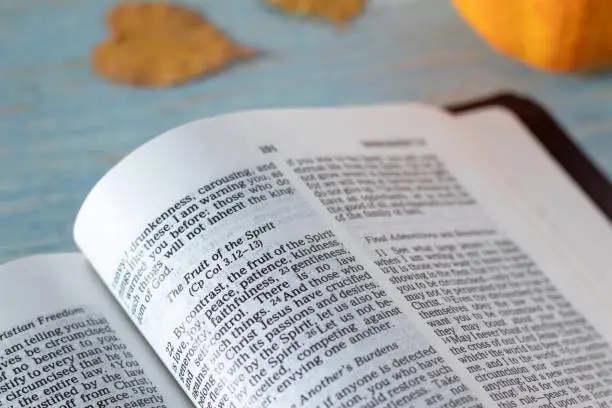 Fruit of the Spirit verses in open holy bible book with pumpkin and autumn leaves in the background. Close-up. Love, joy, peace, Christian spiritual gifts, Galatians 5 Scripture, biblical concept.