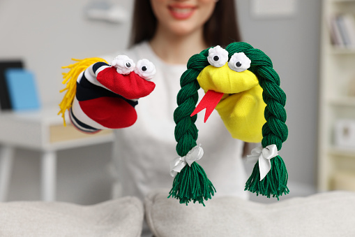 Woman performing puppet show at home, selective focus