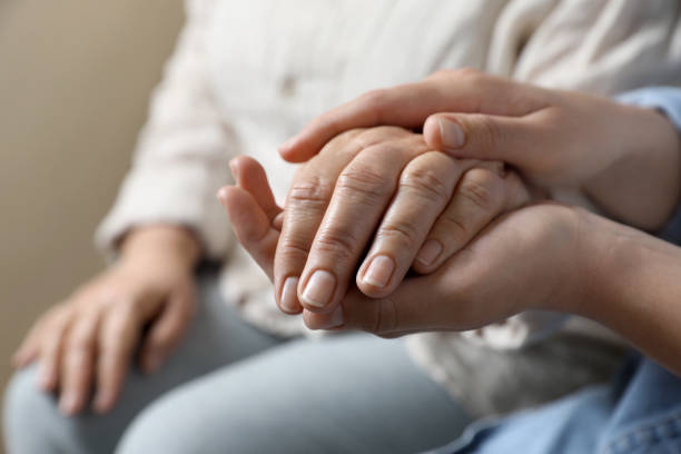 istock Woman holding hands with her mother on beige background, closeup. Space for text 1743463607